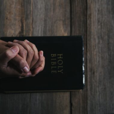 Person praying with a bible on the table